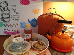 My orange tea setup: tea cosy, kettle, tray with tea cup, honey, cookies.
